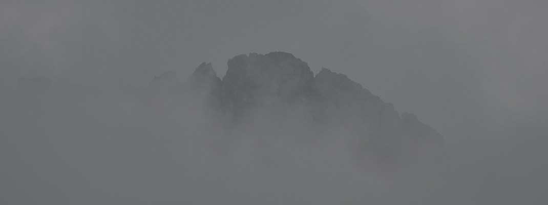Grey mountain ridge in fog.