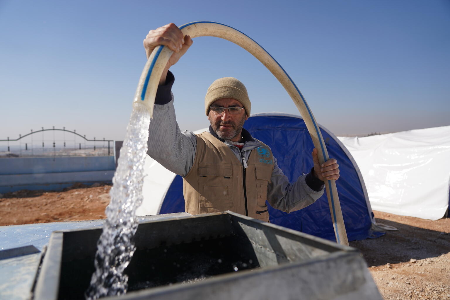 Hope & Resilience in Turkiye & Syria - a UNICEF supported worker delivers safe drinking water to camp for displaced people.