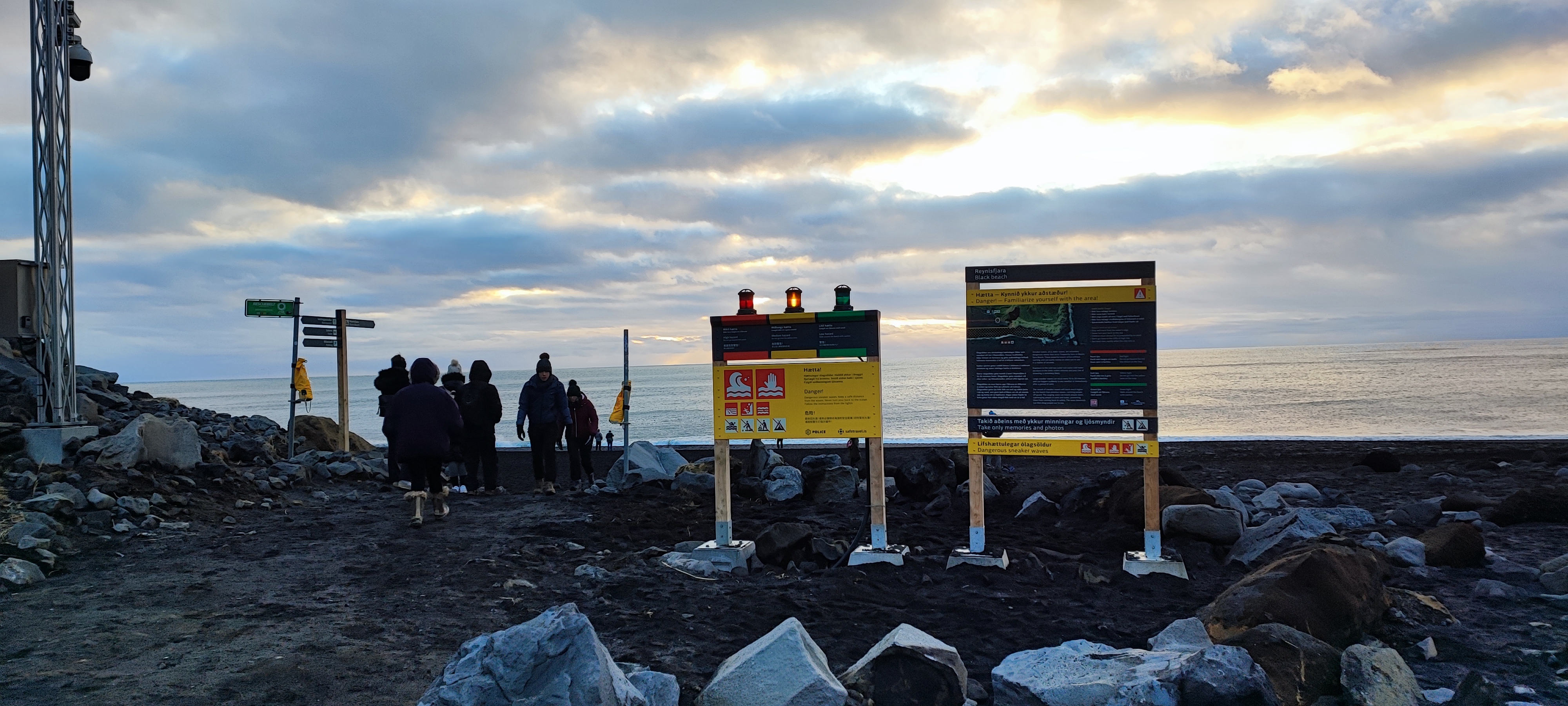 People walking pass warning signs in Reynisfjara