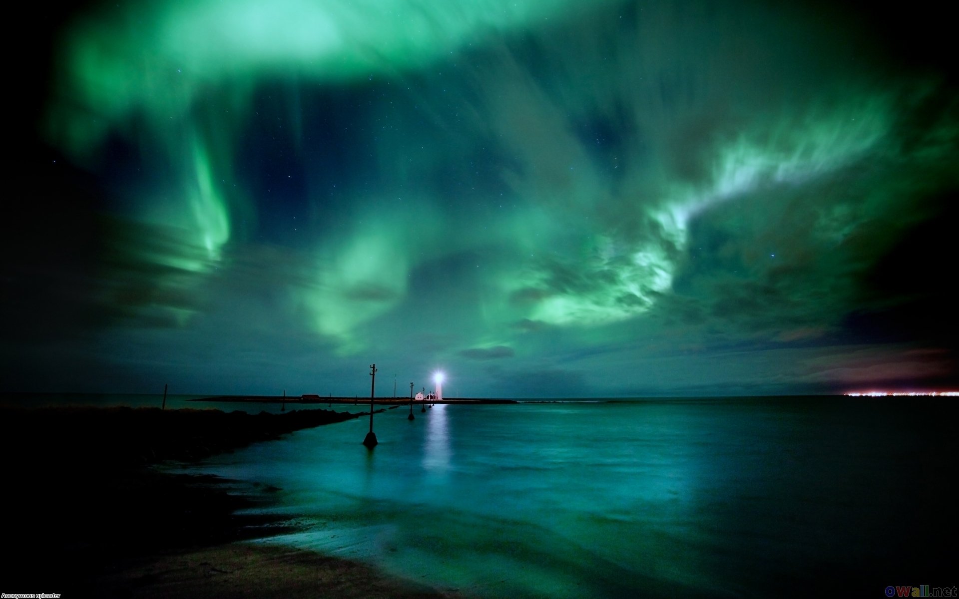 Green northern lights shining above the lighthouse Grótta in Southwest Iceland