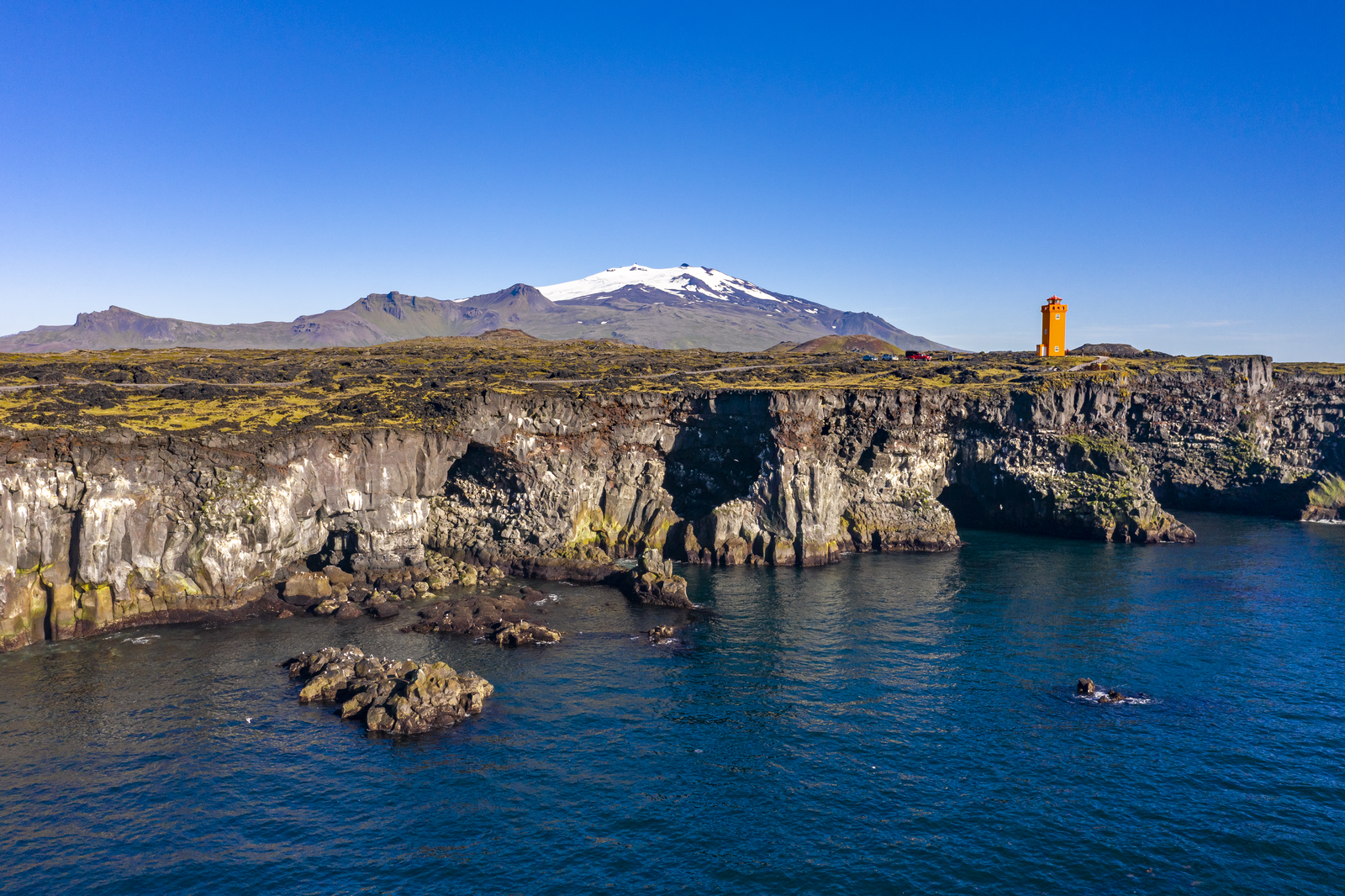 An orange light-house with Snaefellsjokull glacier in background