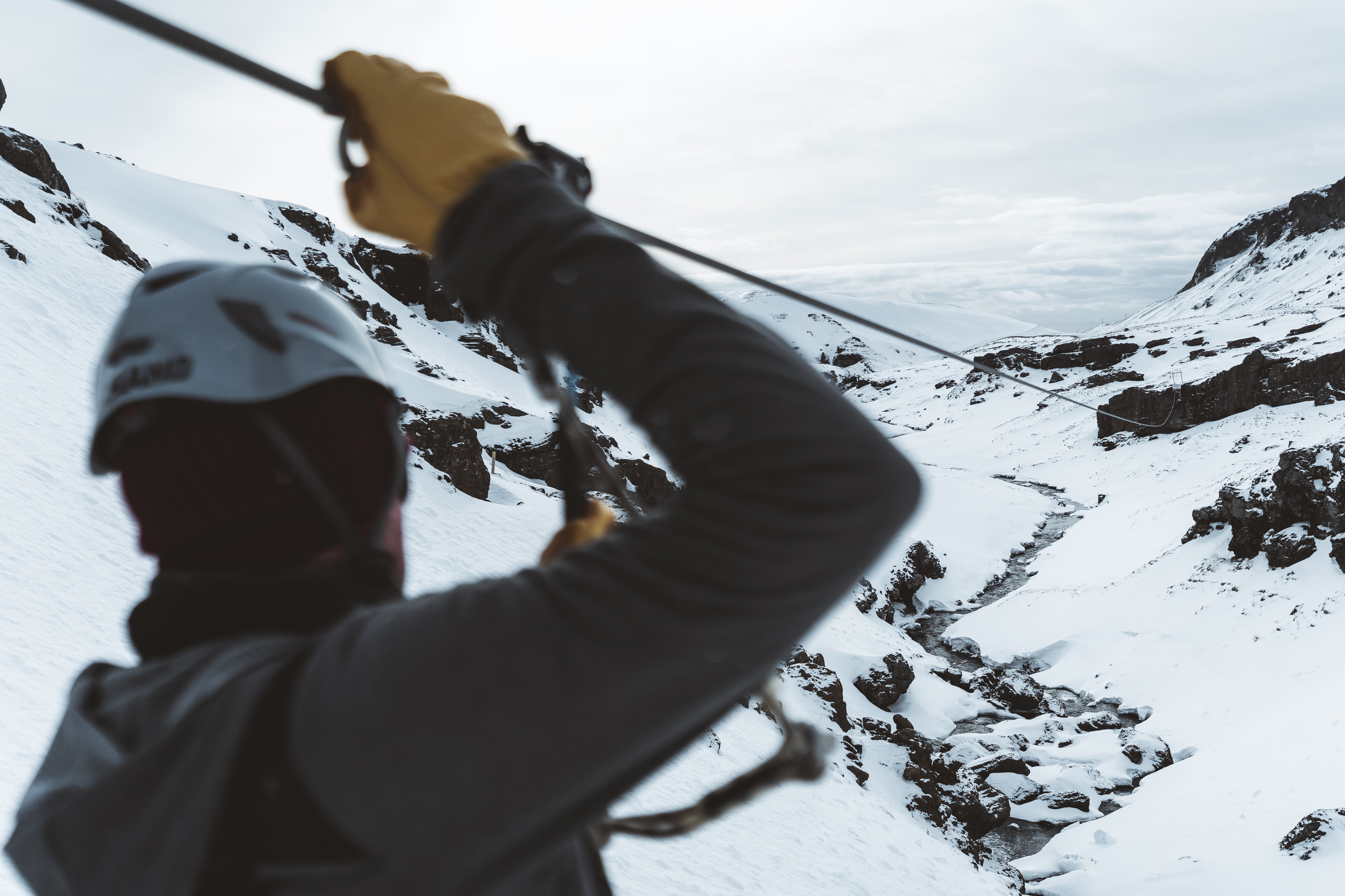 Man ziplining over a canyon covered in snow