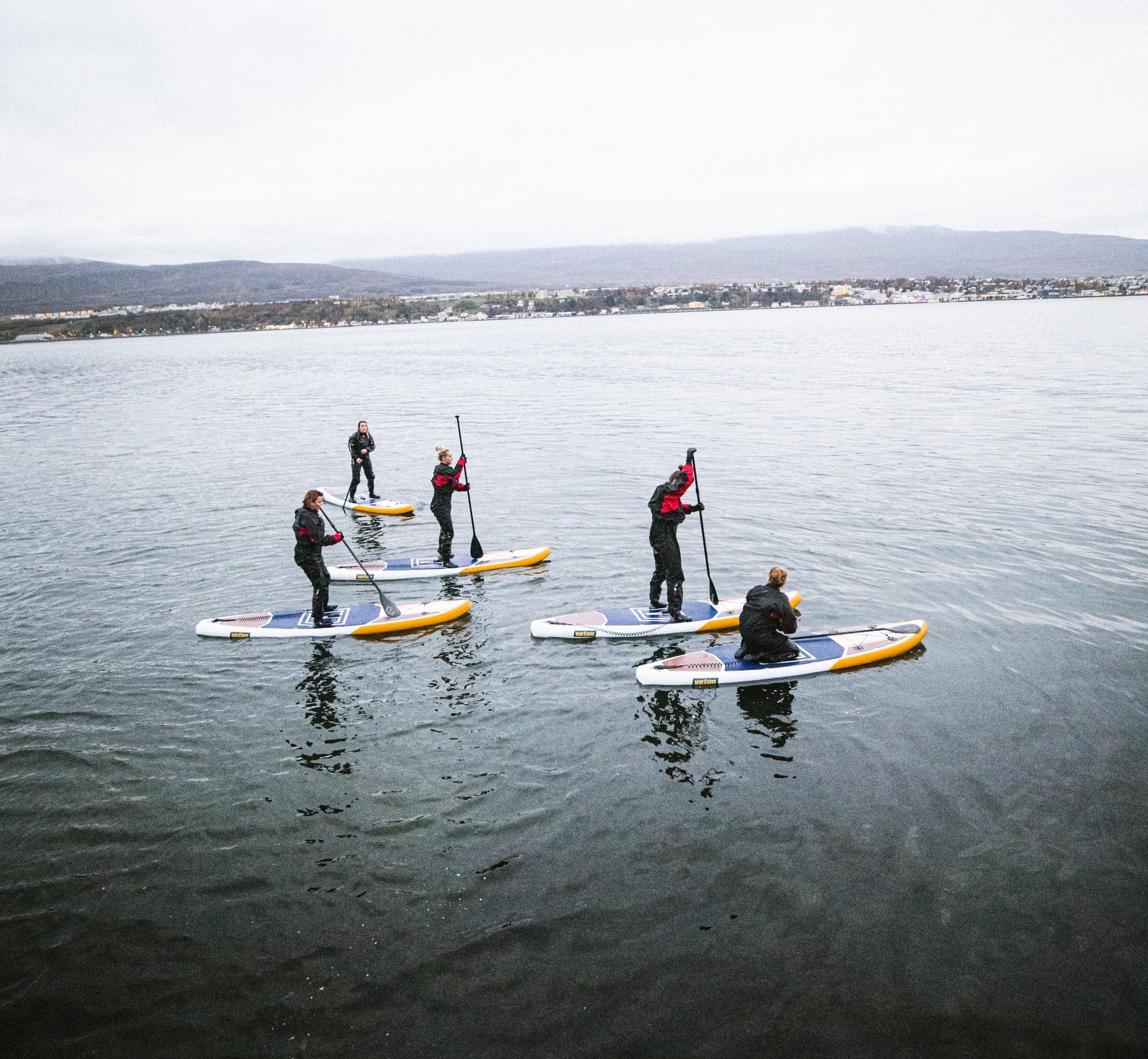 a group of stand-up-paddleboarders on a fjord