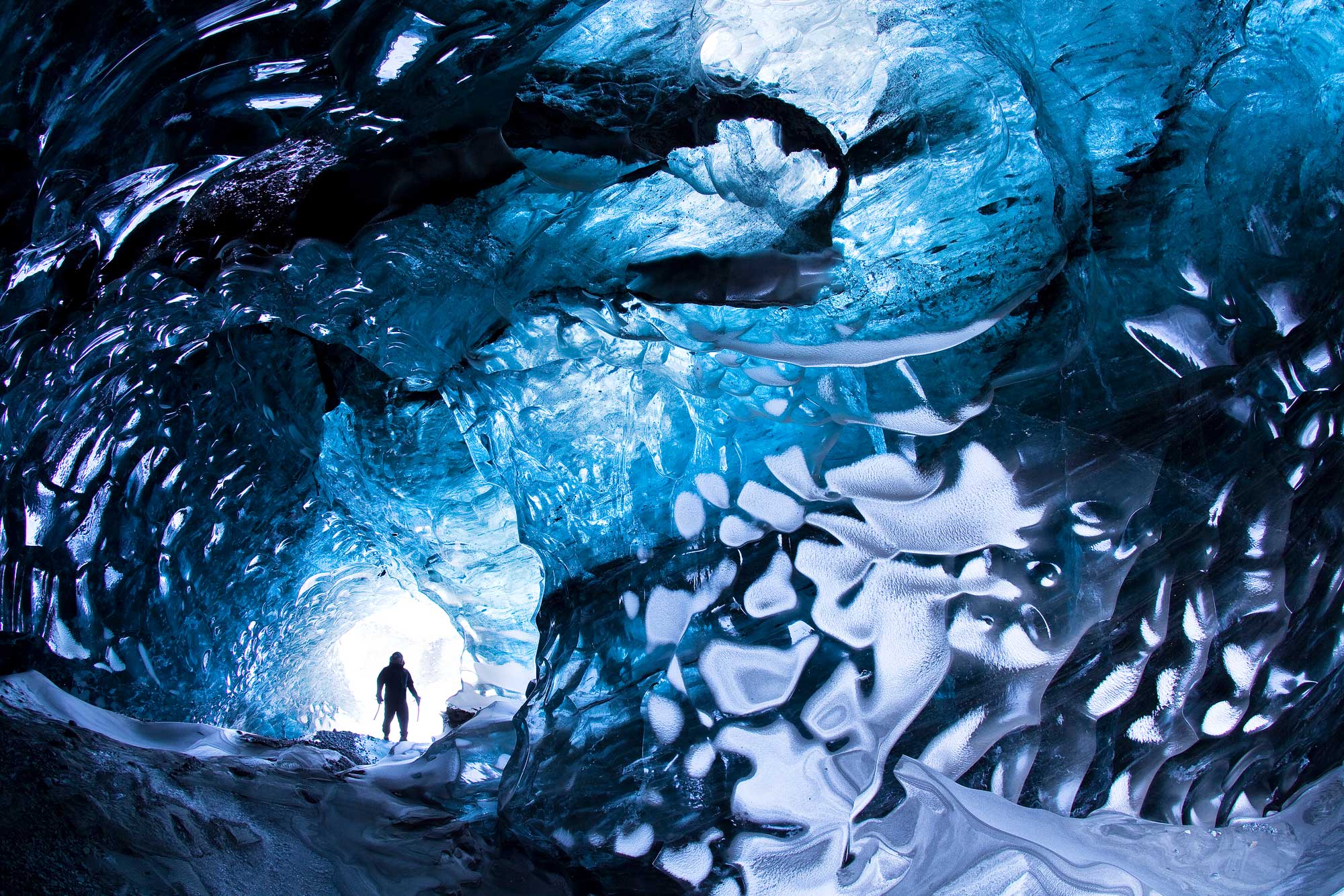A man inside a blue ice tunnel