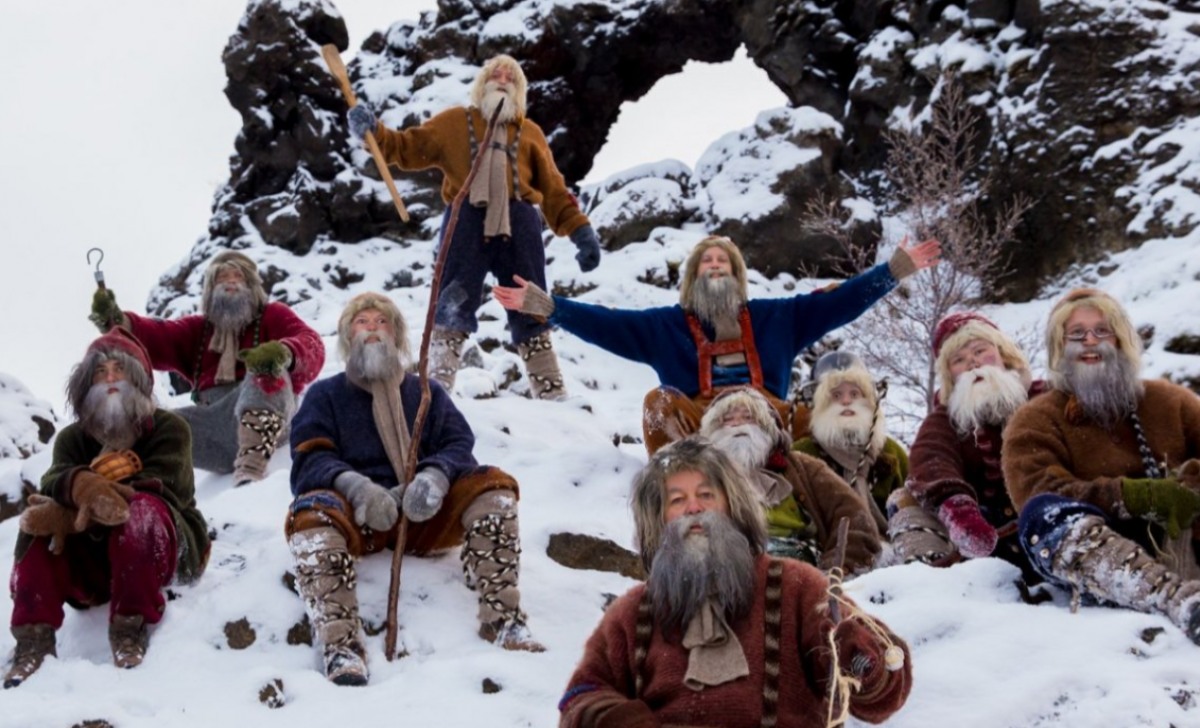 Several bearded figures wearing wool clothes sitting on a snowy ground