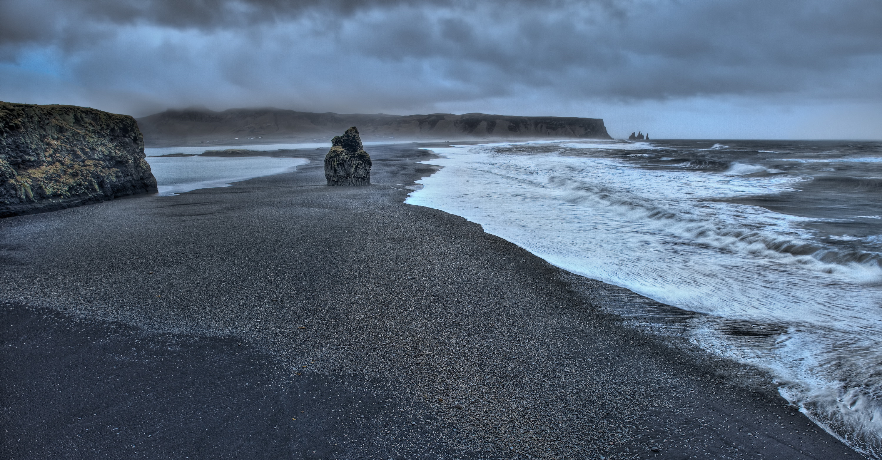 Black sand beach with waves crashing on the shore