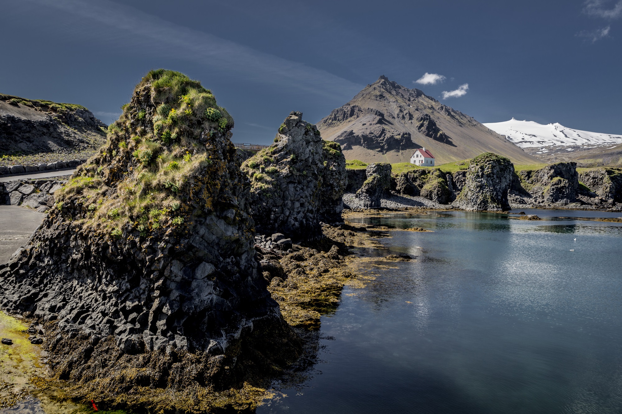 Bastalt stacks rising from a coastline with mountains in the back