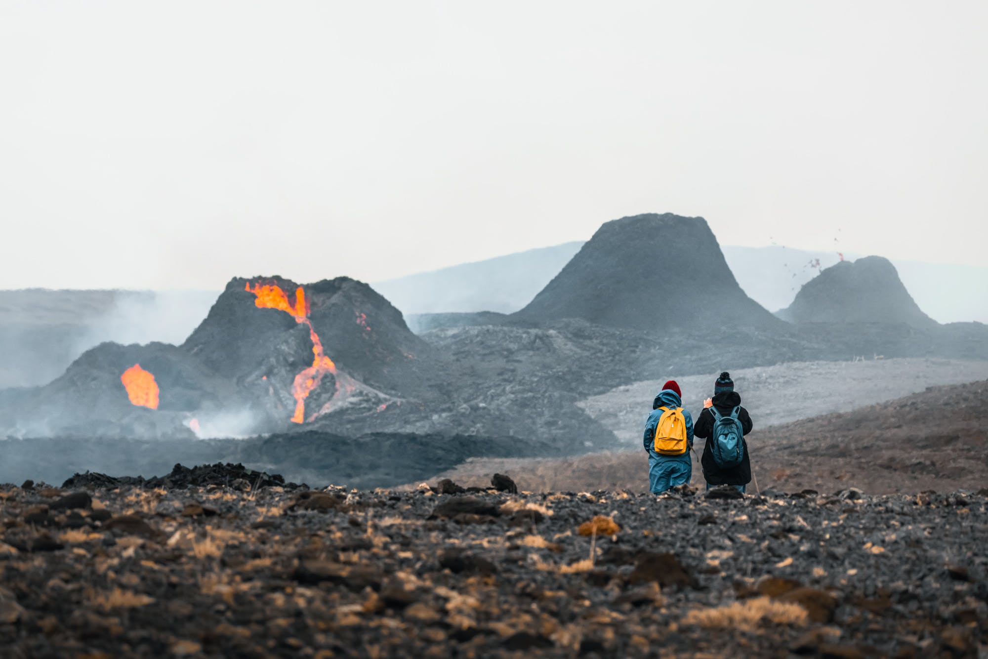 Two people standing in front of a row of erupting craters