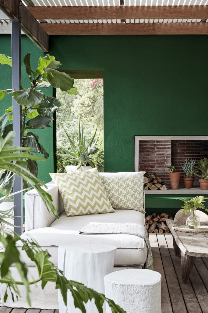 Dark green (Puck) outside living area with panelled wooden floor, cream sofas and a wooden table.