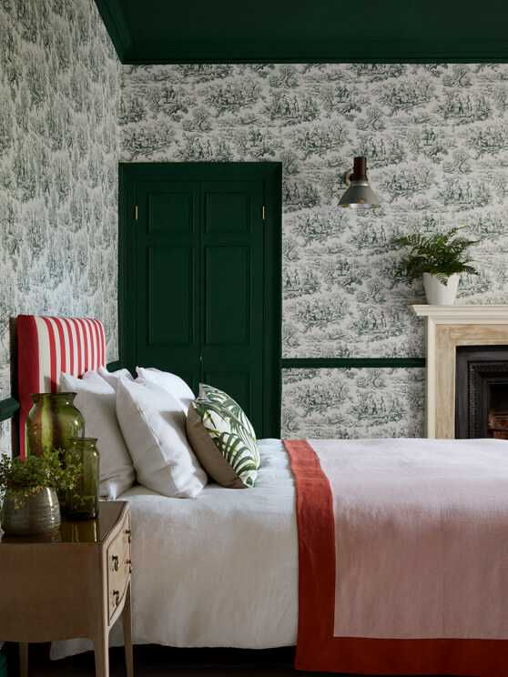 Bedroom with dark green French Toile wallpaper (Lovers' Toile - Puck), dark green (Puck) door and ceiling and white bedding.