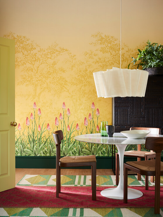 Dining room with yellow mural wallpaper (Upper Brook Street - Soleil) and a dining room table with wooden chairs.